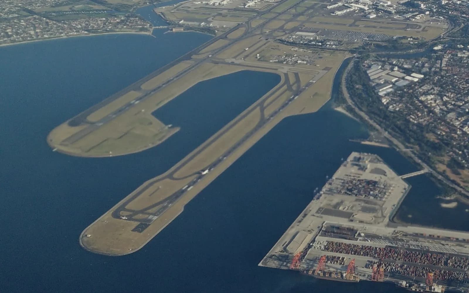 Aerial view of Sydney Airport, its runways reaching into Botany Bay